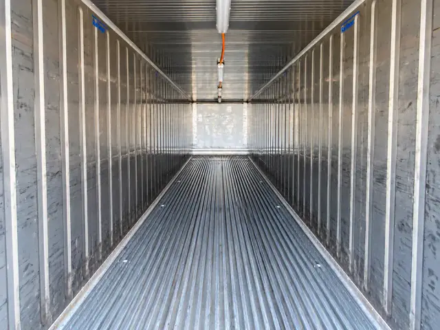 Interior de un contenedor refrigerado: paredes de aluminio corrugado, piso ranurado y conductos de aire en el techo